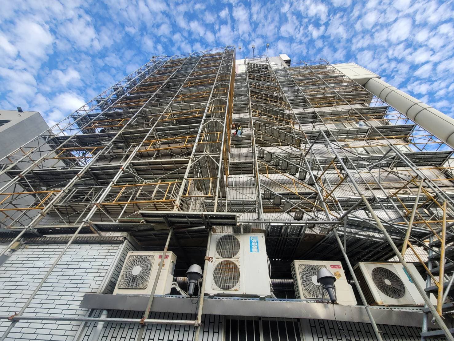 由下方仰望中台南港講堂整修鷹架，柏凱鷹架工程精密規劃之垂直與水平作業平台，完全符合法規工安標準。