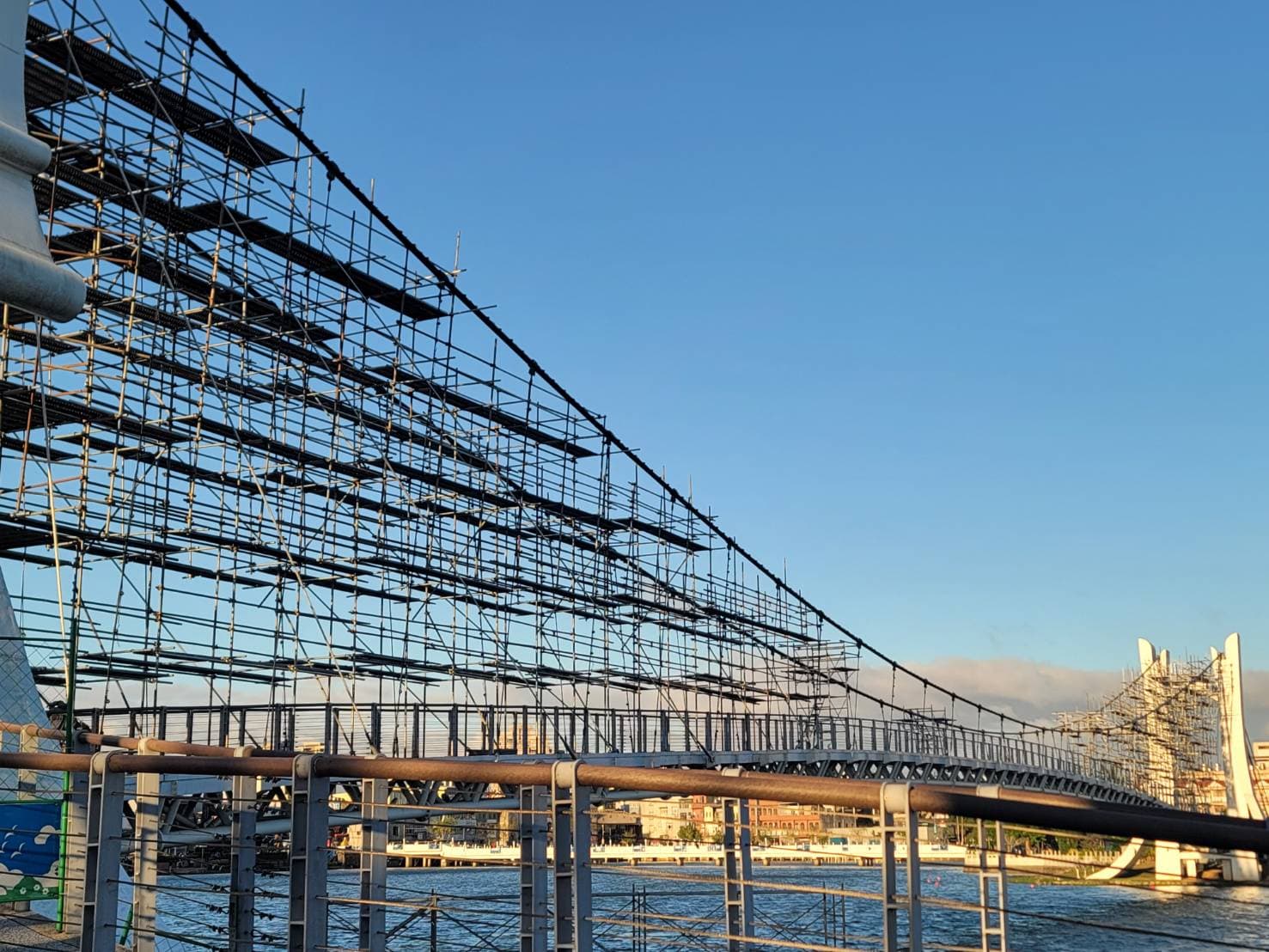 柏凱鷹架工程於桃園龍潭大池吊橋兩側搭設之大型系統式施工架，展示橋身維護工程的嚴密結構與專業施工平面。