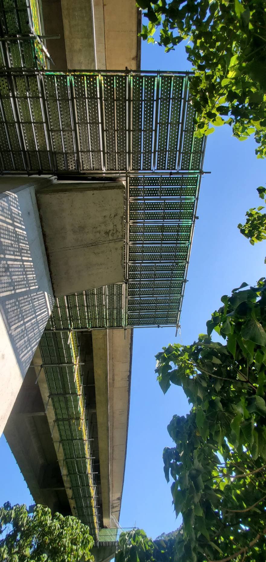 柏凱鷹架工程架設之北二高懸吊式施工架仰視全景，展示橋樑底部的金屬工作平台與安全防護網網，專為國道橋樑耐震補強工程設計的大型施工架系統。